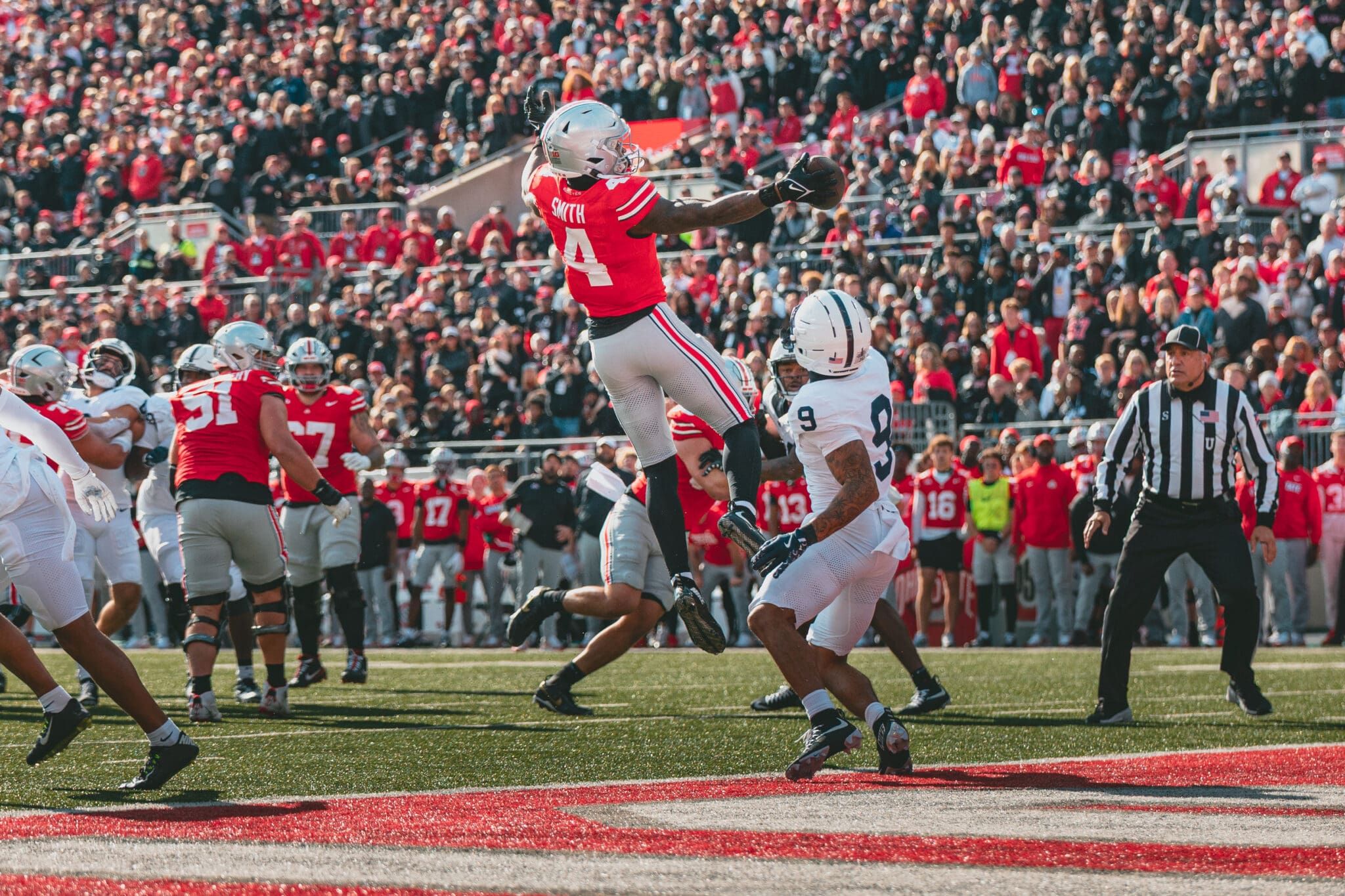 Jeremiah Smith leaps and stretches over a Penn State defender to make a one handed touchdown catch.